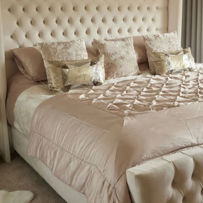 Three-quarter angle view of The Astoria Cream Velvet Bed Frame showcasing the tall tufted headboard, satin quilted runner, and elegant decorative pillows
